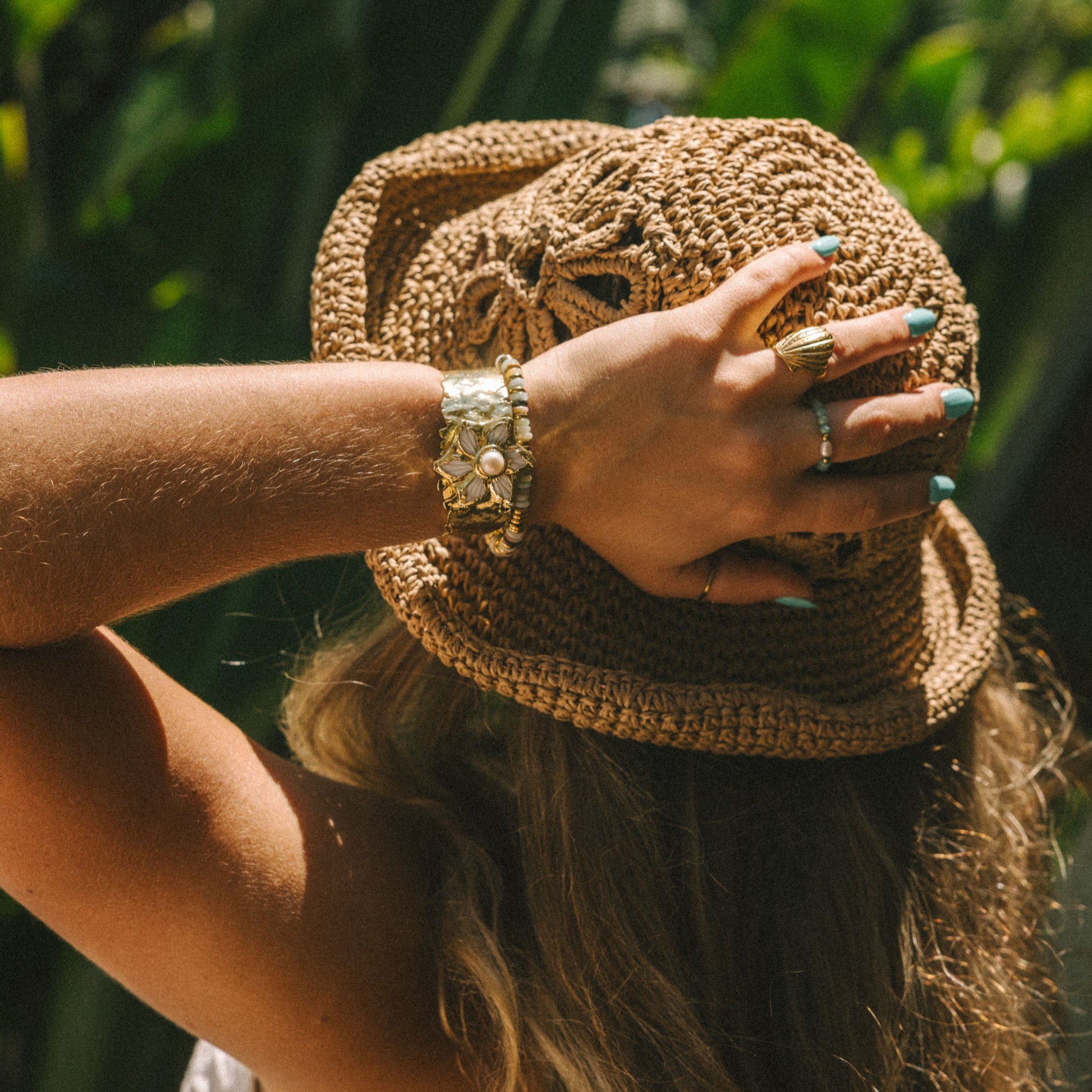Person holding a woven bag with a blurred natural background