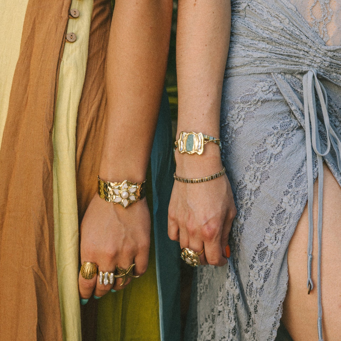 Two people wearing jewelry with a blurred natural background