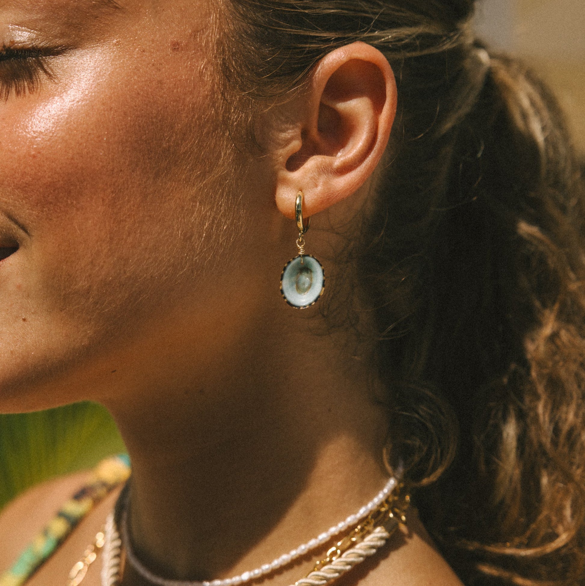 Close-up of a woman wearing gold necklaces and earrings with a blurred background