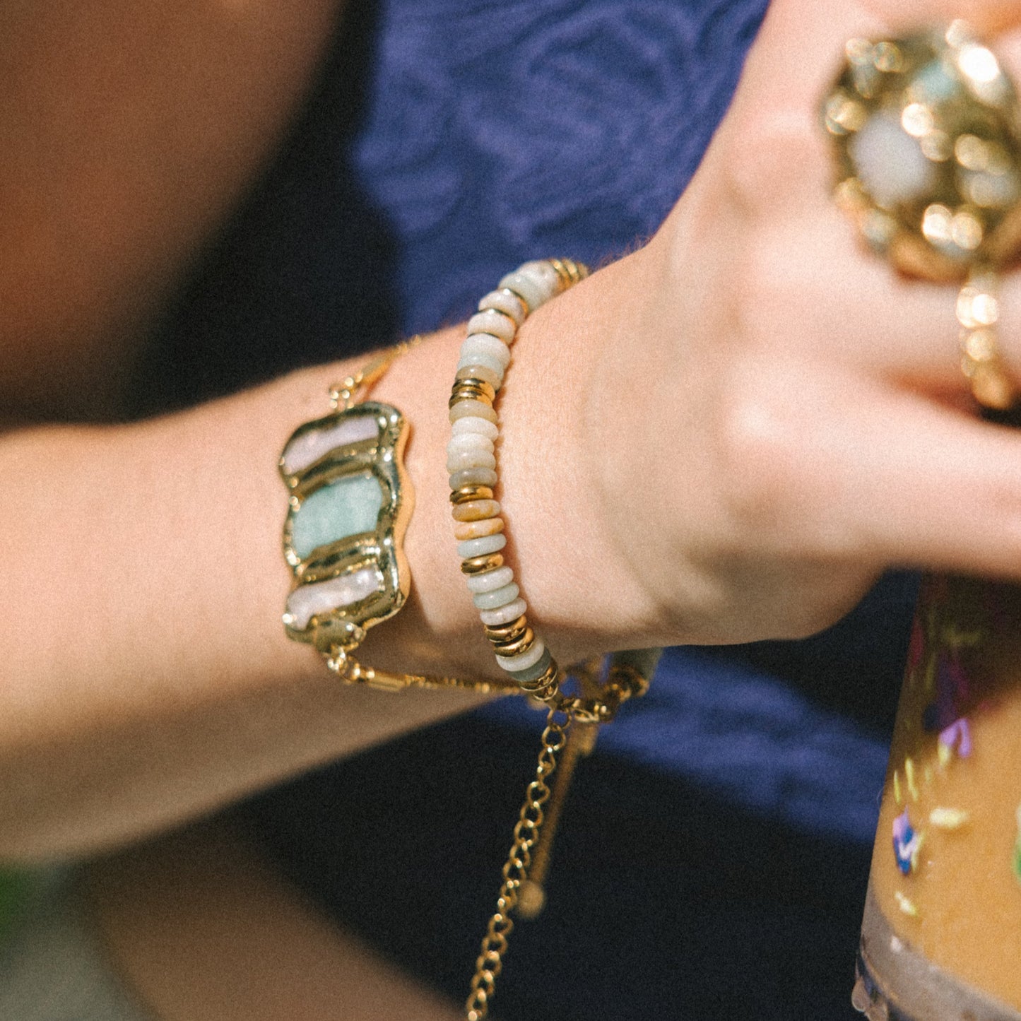 Close-up of hands wearing gold rings and bracelets with a blurred background
