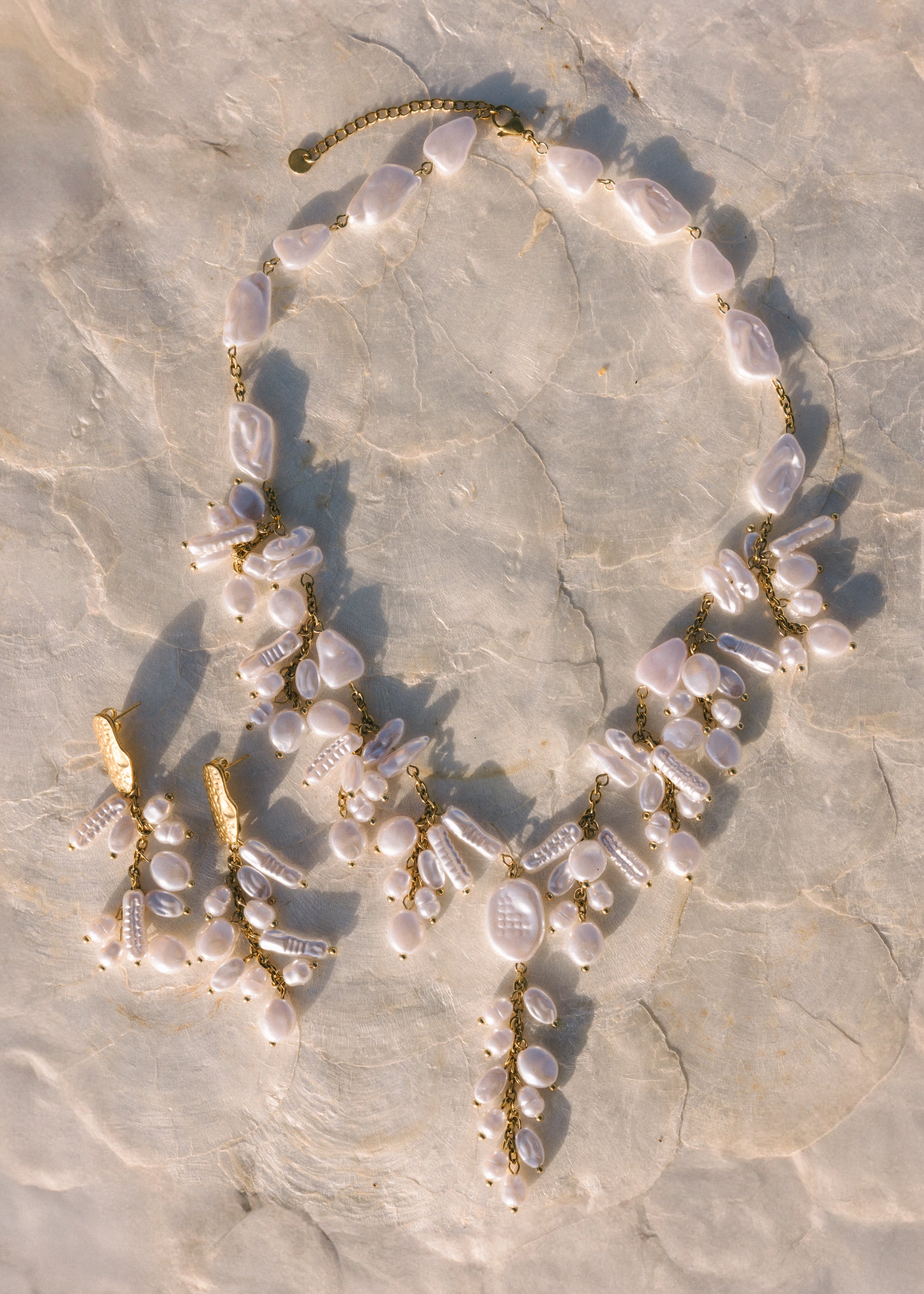 Necklace with pearls and gold accents on a textured stone surface