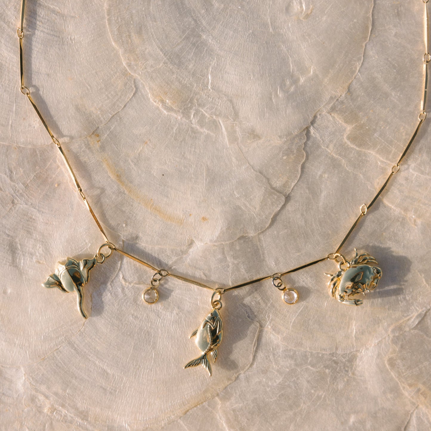 Gold necklace with leaf-shaped pendants on a marble surface