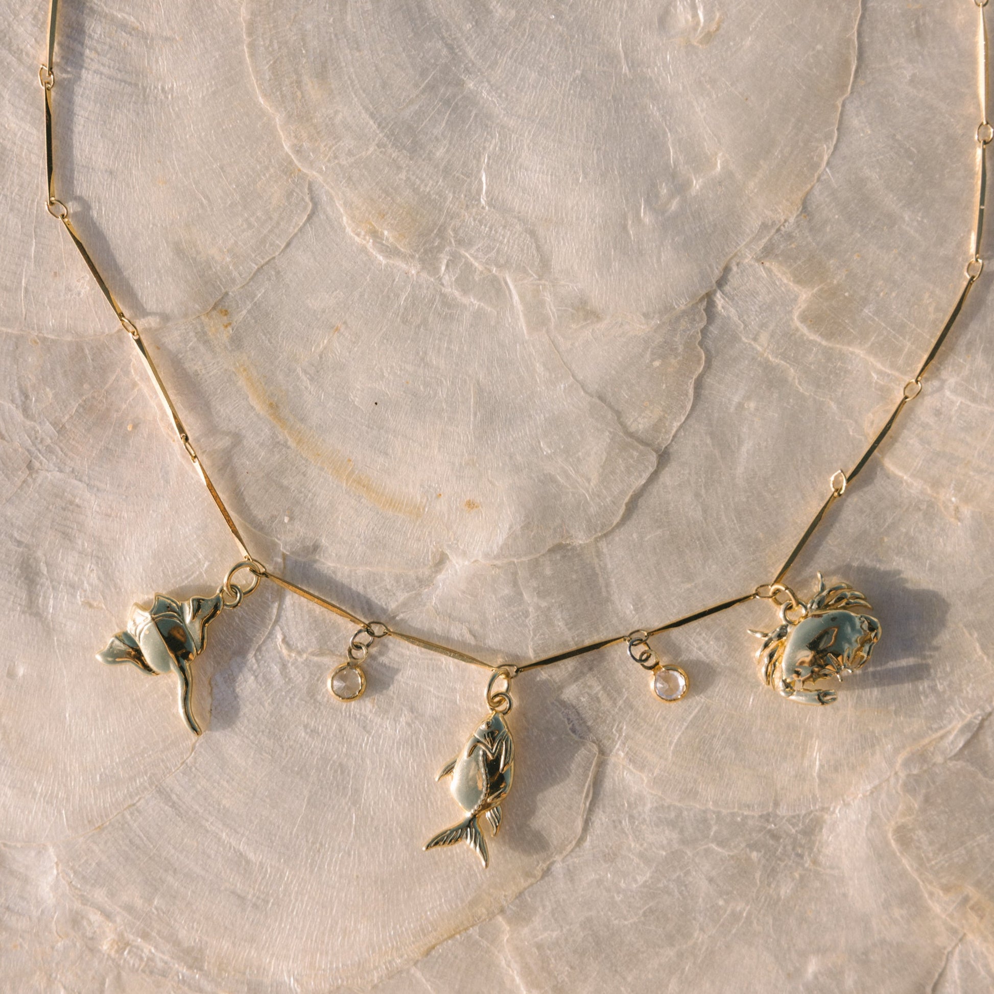 Gold necklace with leaf-shaped pendants on a marble surface