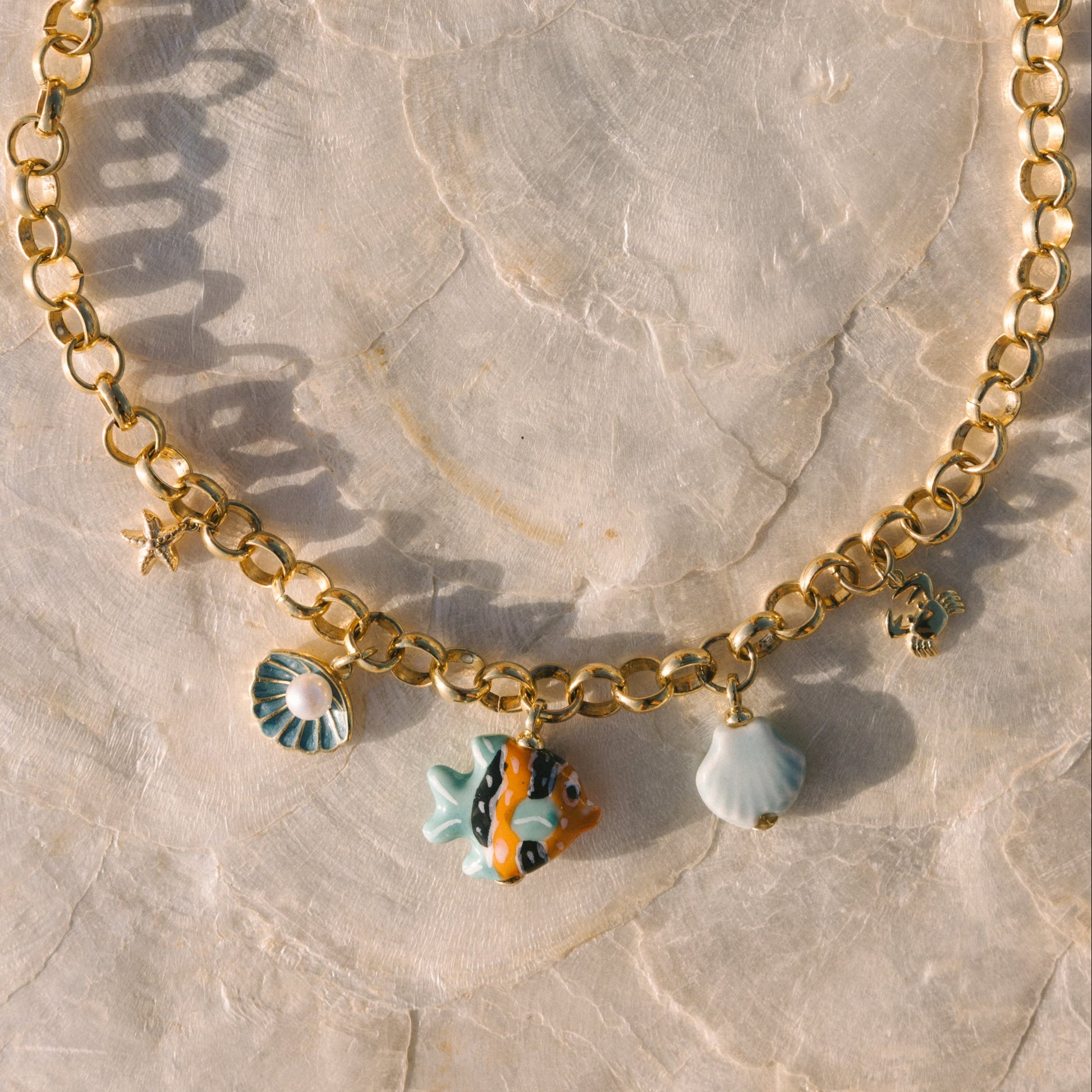 Gold chain bracelet with charms on a marble surface