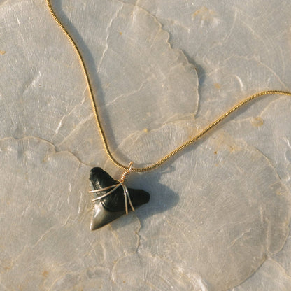 Necklace with a heart-shaped black stone pendant on a textured surface