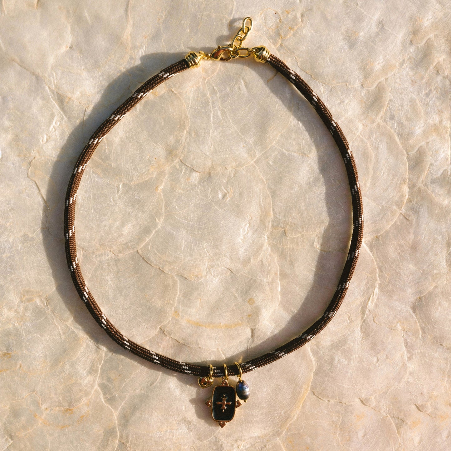 Necklace with black and gold details on a light marble background