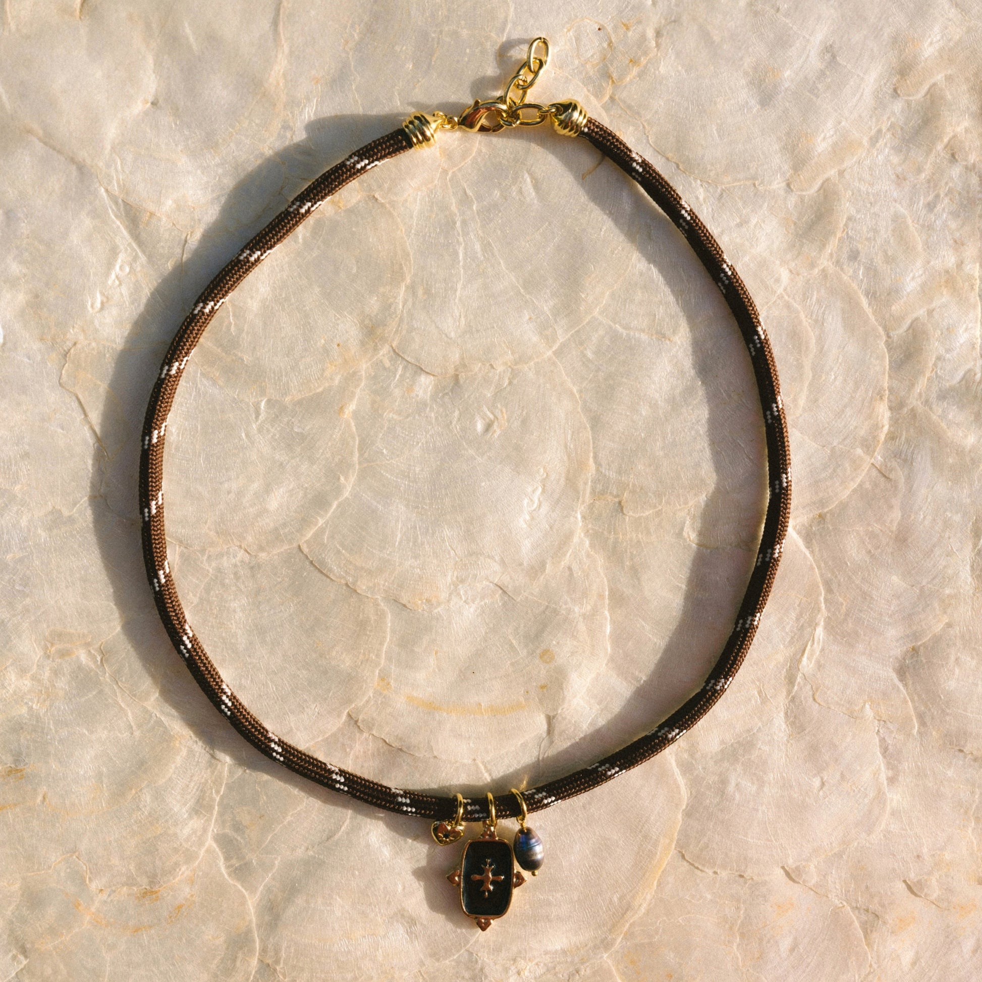 Necklace with black and gold details on a light marble background