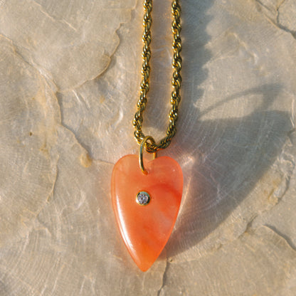 Heart-shaped orange pendant necklace on a textured stone surface