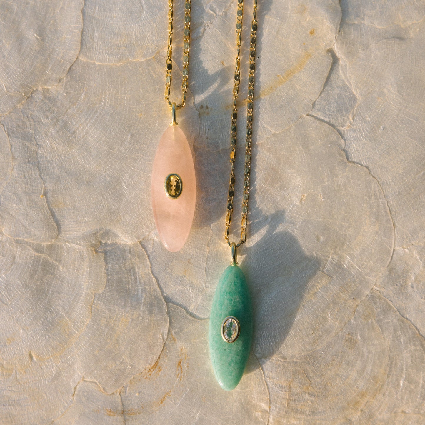 Necklace with pink and green pendant on a textured stone surface