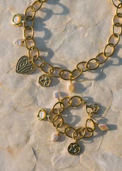 Gold bracelet with heart-shaped charms on a stone surface