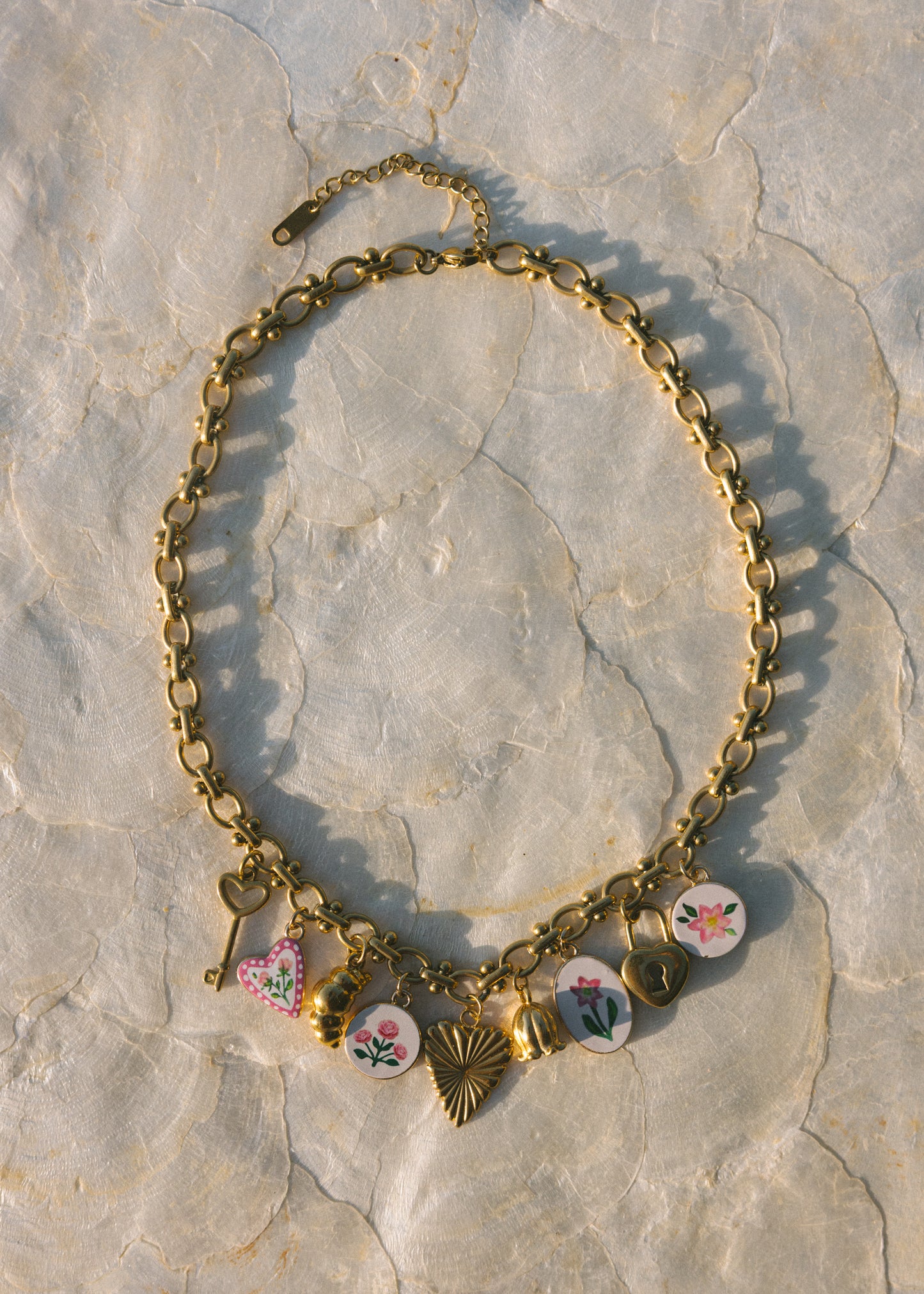 Gold necklace with floral charms on a stone surface