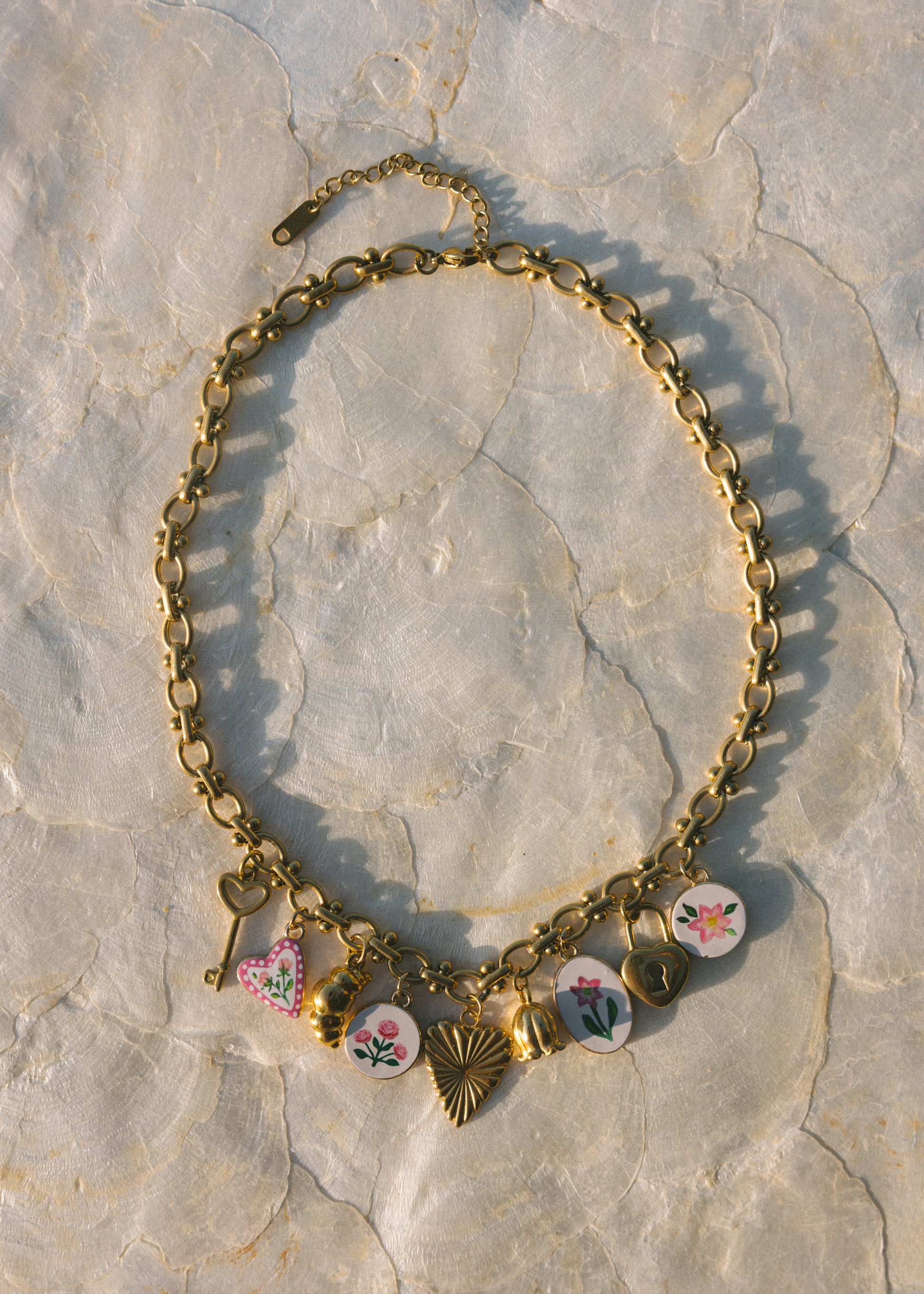 Gold necklace with floral charms on a stone surface