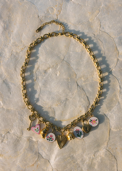 Gold necklace with floral charms on a stone surface