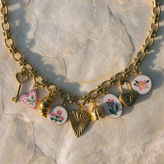 Gold necklace with various charms on a stone surface