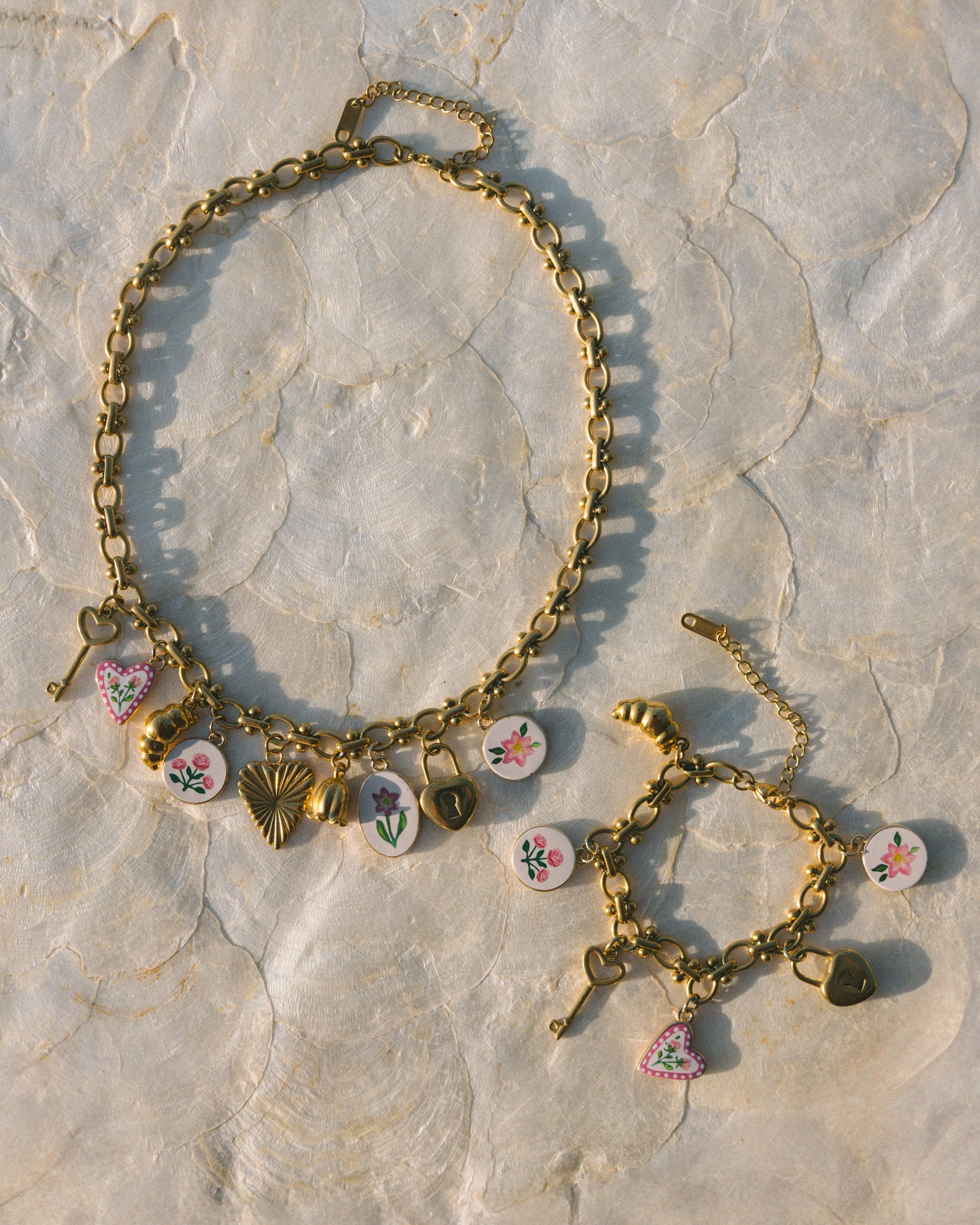 Gold bracelet with colorful charms on a stone surface