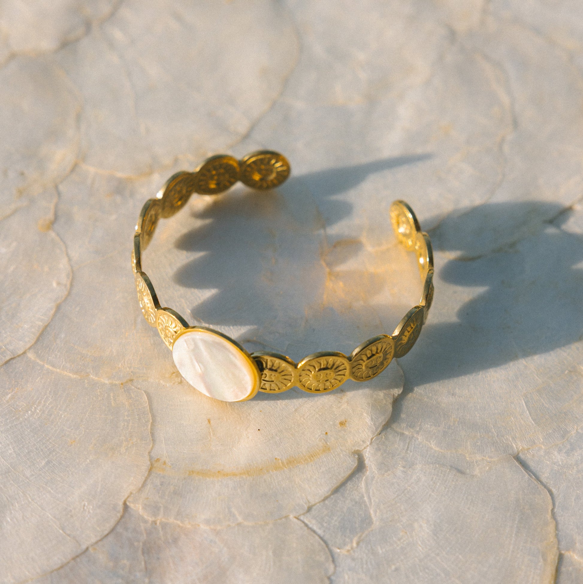 Gold bracelet with shell elements on a textured stone surface