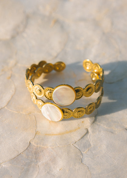Gold bracelet with circular designs on a textured surface