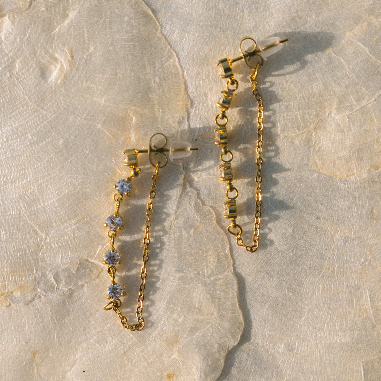 Gold chain necklace with blue stones on a stone surface