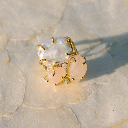 Gold ring with a large central gemstone and smaller stones on a textured surface