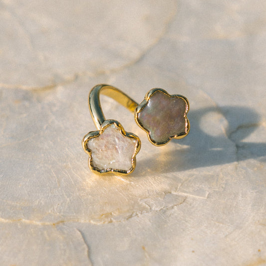Gold ring with a star-shaped stone on a textured beige surface
