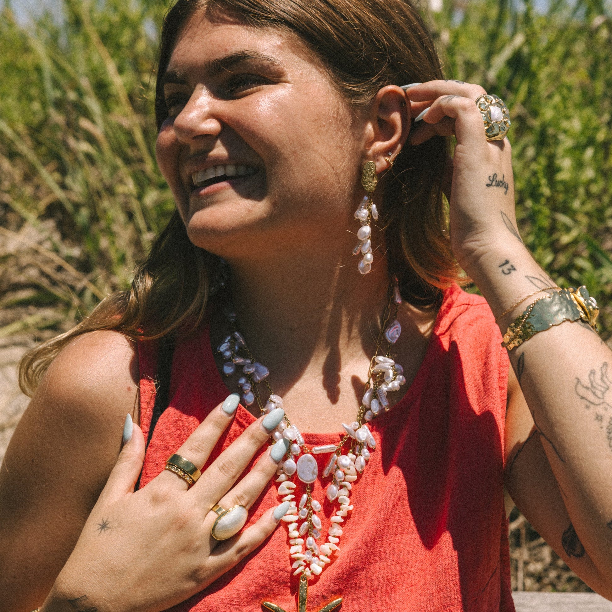 Woman wearing a red top with starfish design, surrounded by greenery