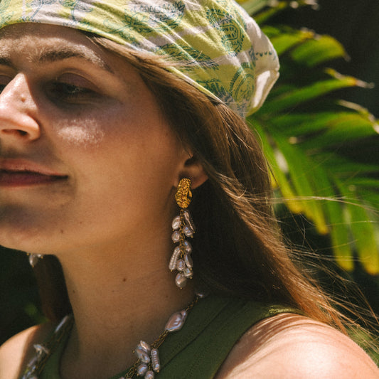 Woman wearing a green headscarf and jewelry with a blurred natural background