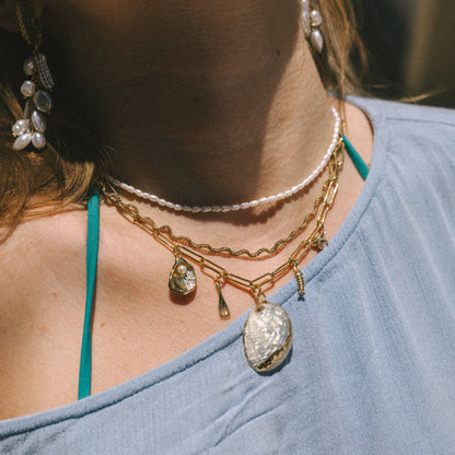 Close-up of a person wearing multiple necklaces with pendants on a blurred background