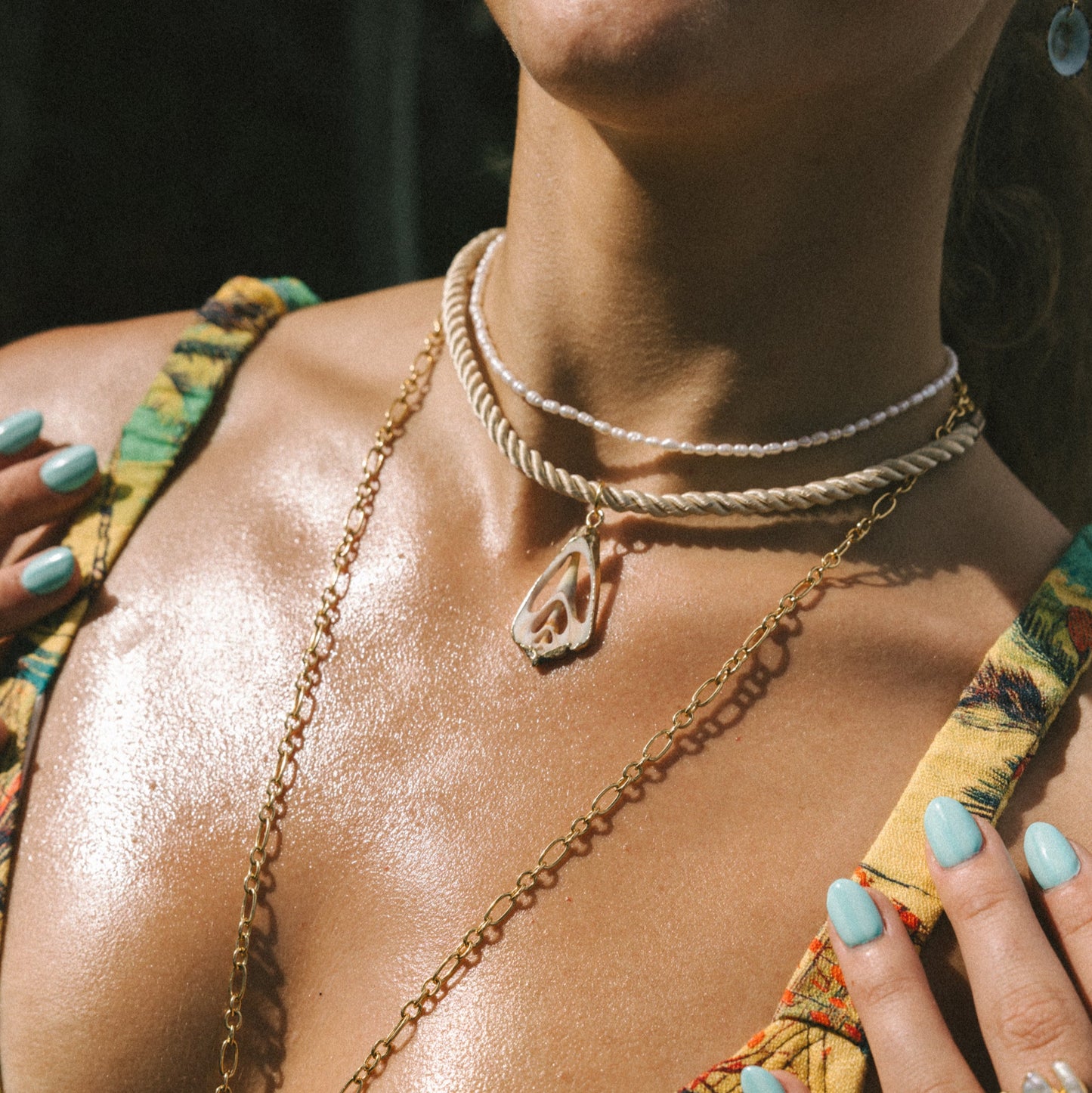 Close-up of a person wearing gold necklaces and a yellow top with green accents.