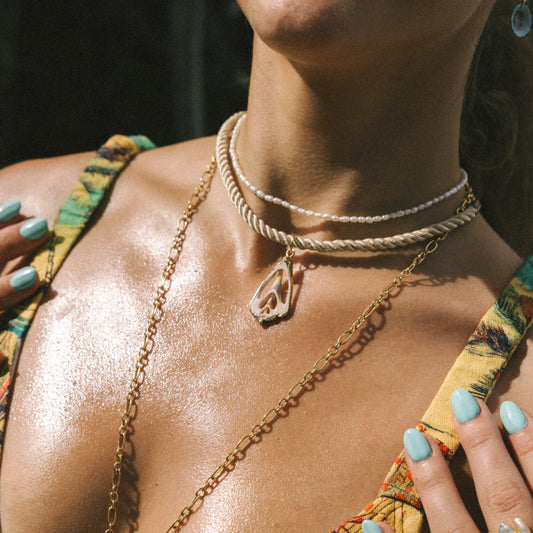 Close-up of a person wearing gold necklaces and a yellow top with green accents.