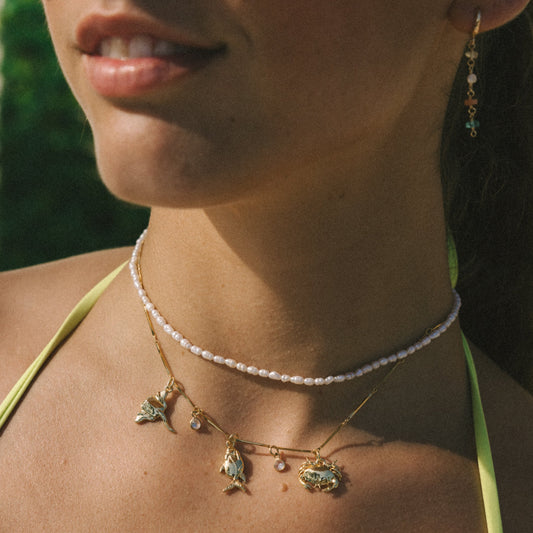 Close-up of a person wearing a necklace with pendant charms outdoors