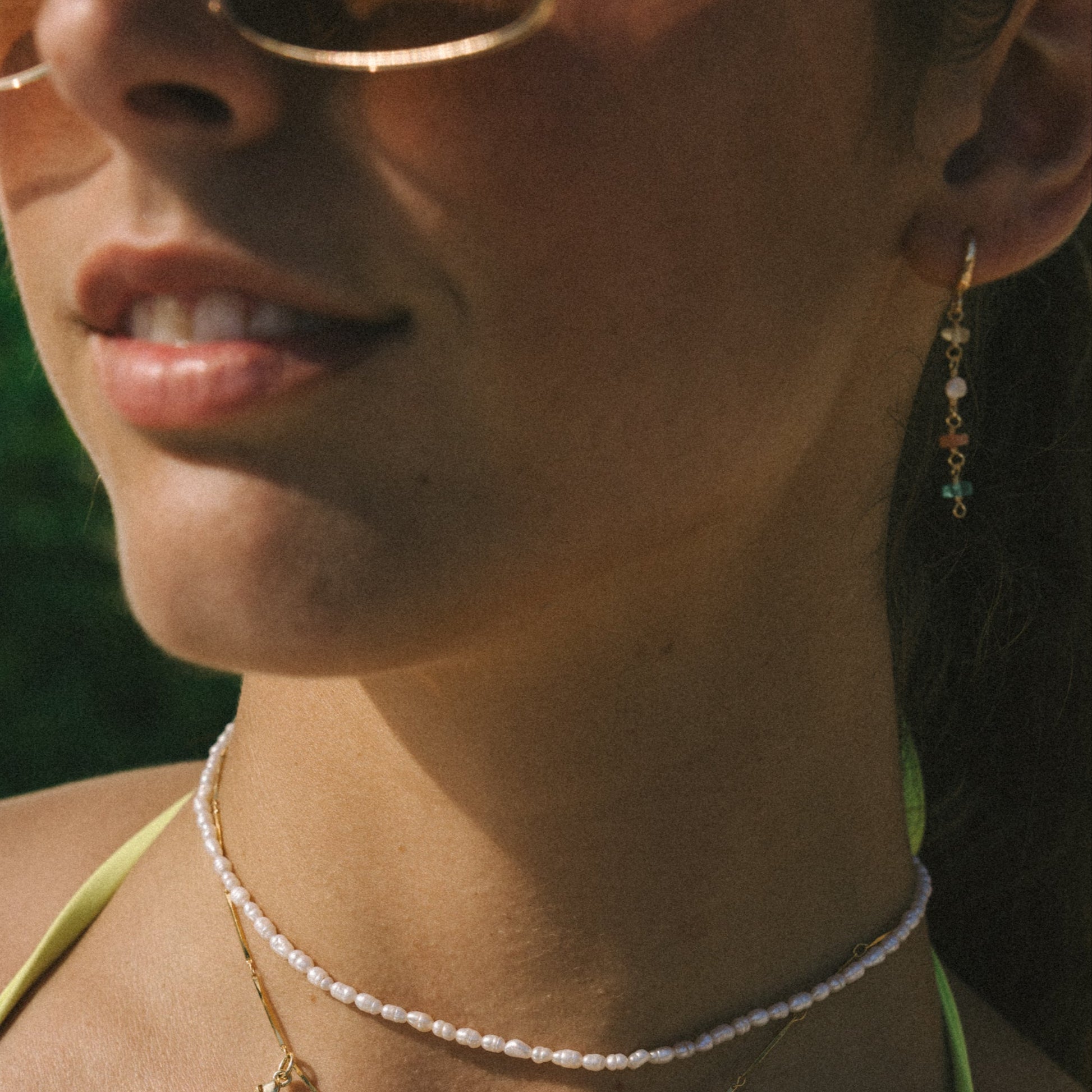 Close-up of a person wearing a necklace with pendant charms outdoors