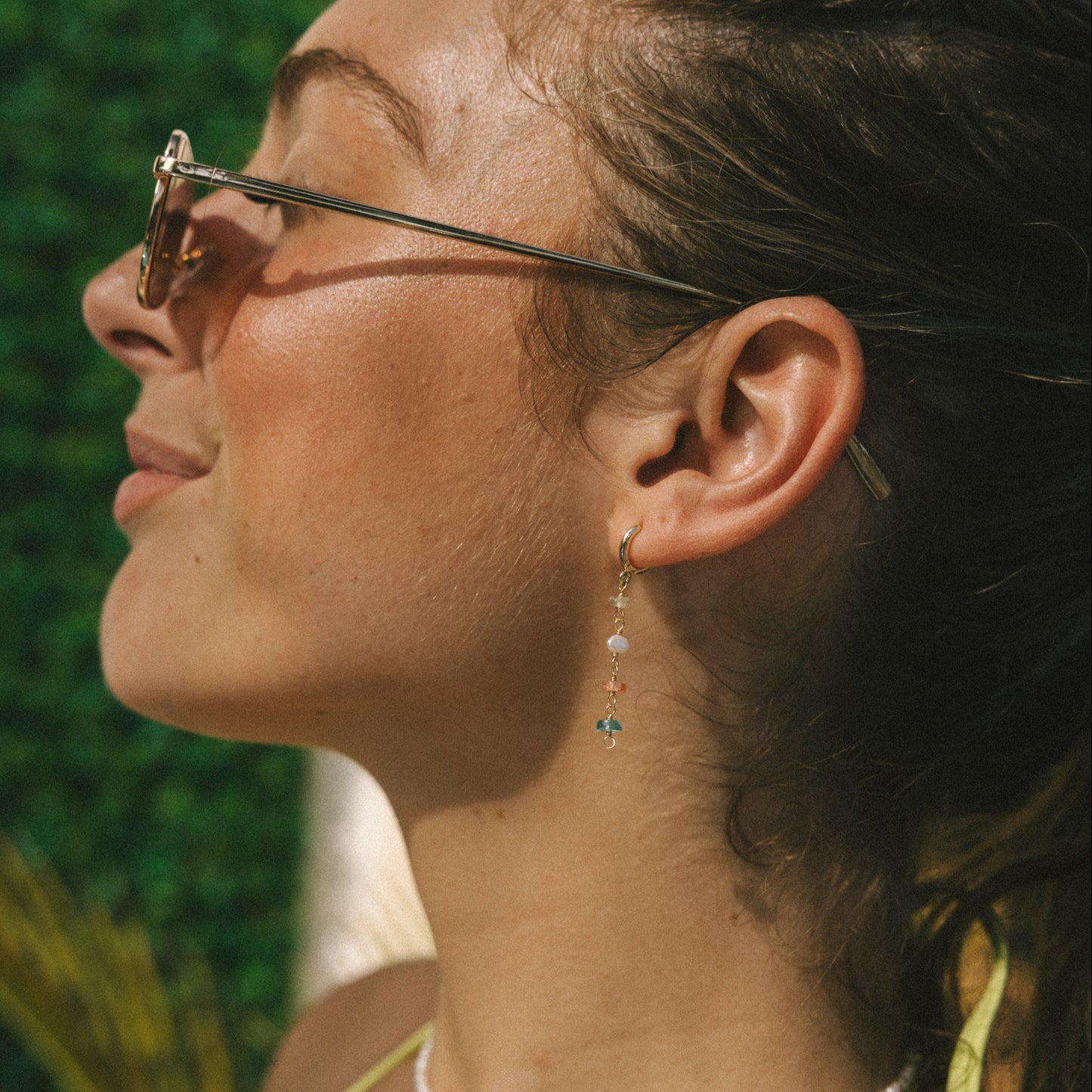 Woman wearing sunglasses with a blurred green background