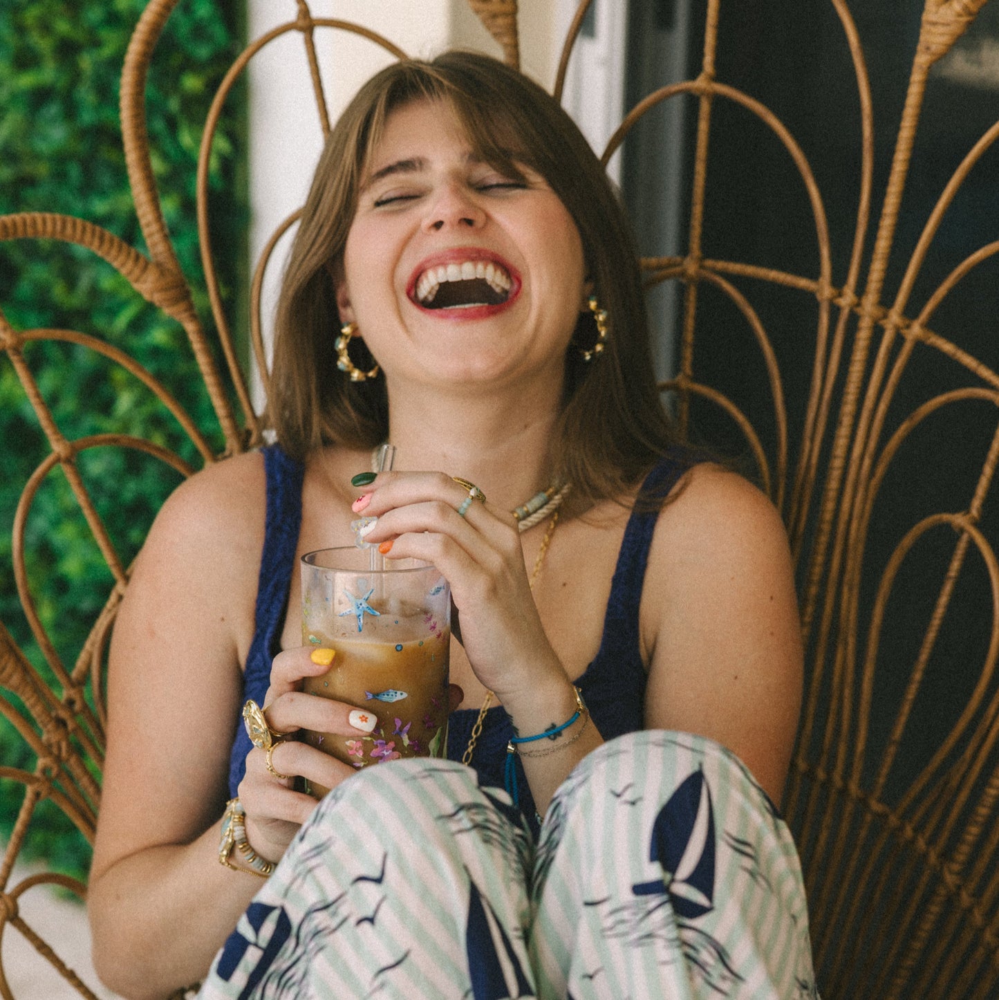 Woman laughing and holding a drink in an outdoor setting