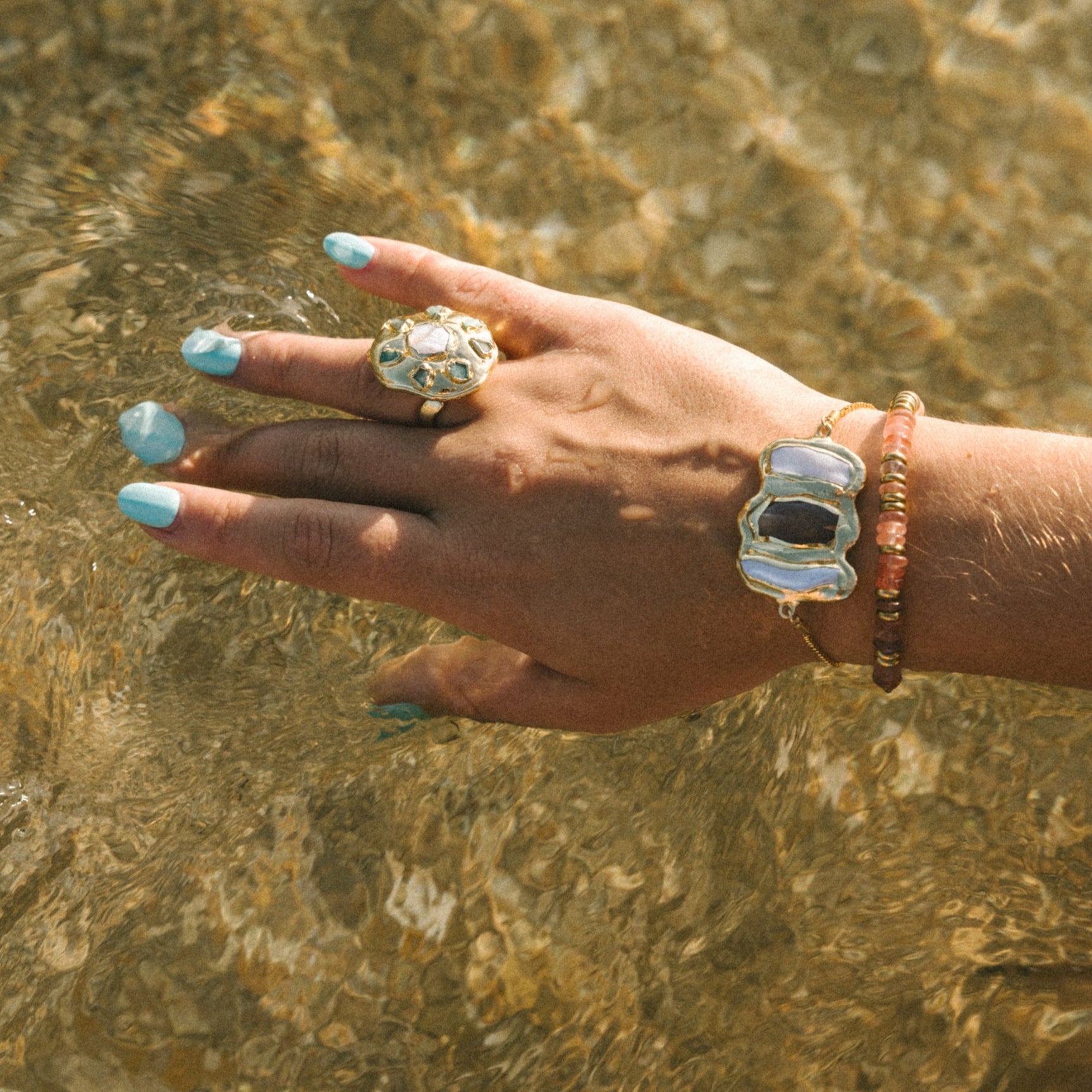 Hand with rings and bracelets touching clear water