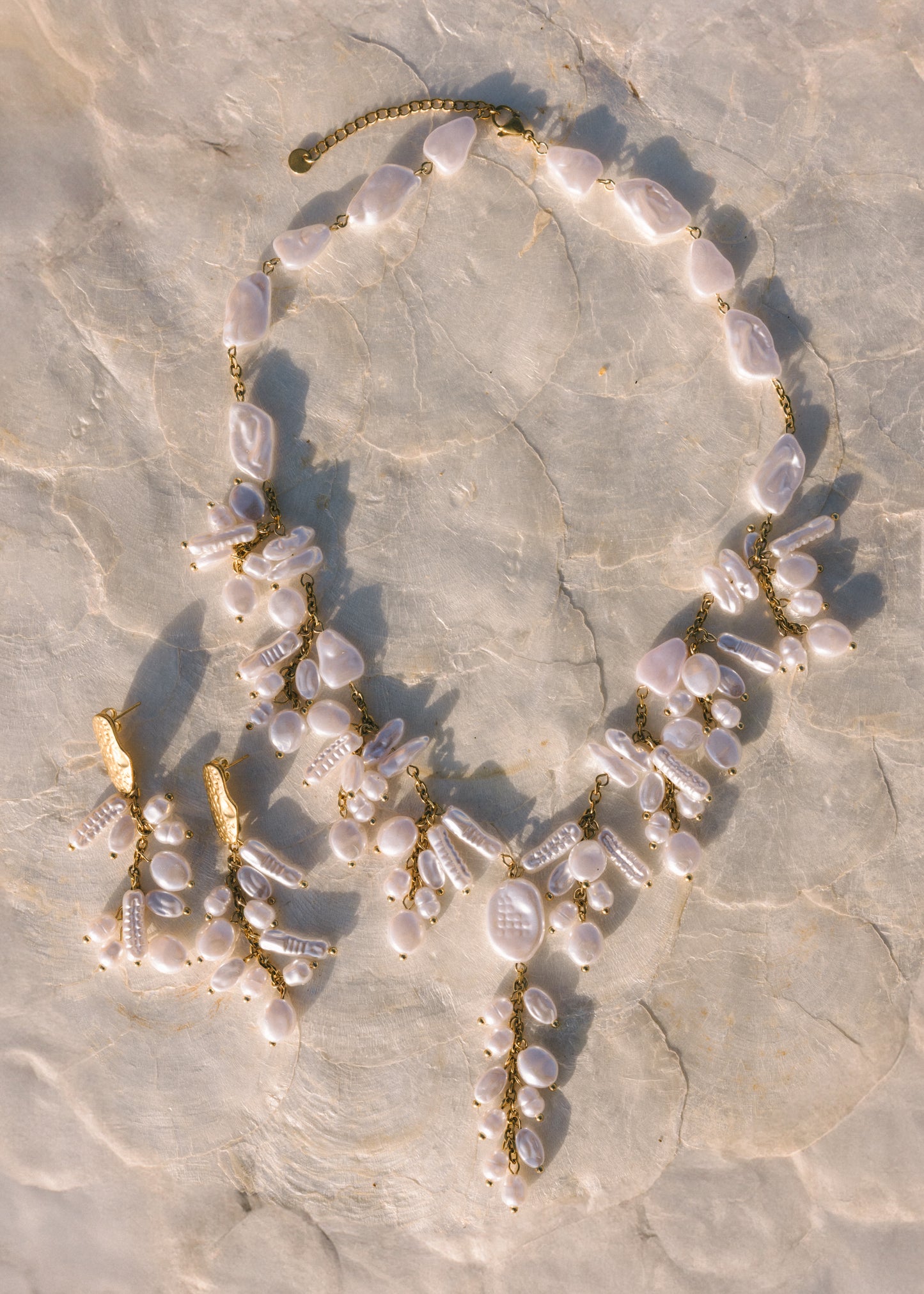 Necklace with pearls and gold accents on a textured stone surface