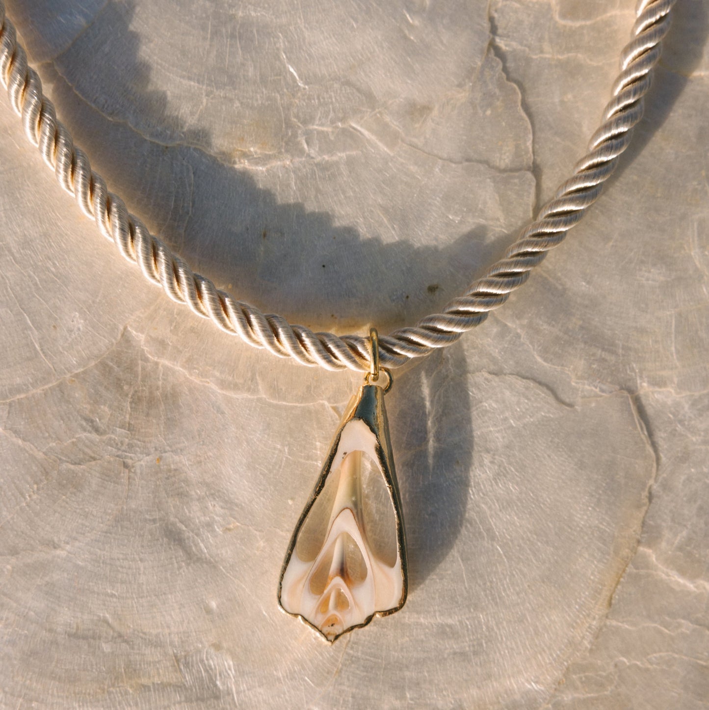 Necklace with a shell pendant on a stone surface