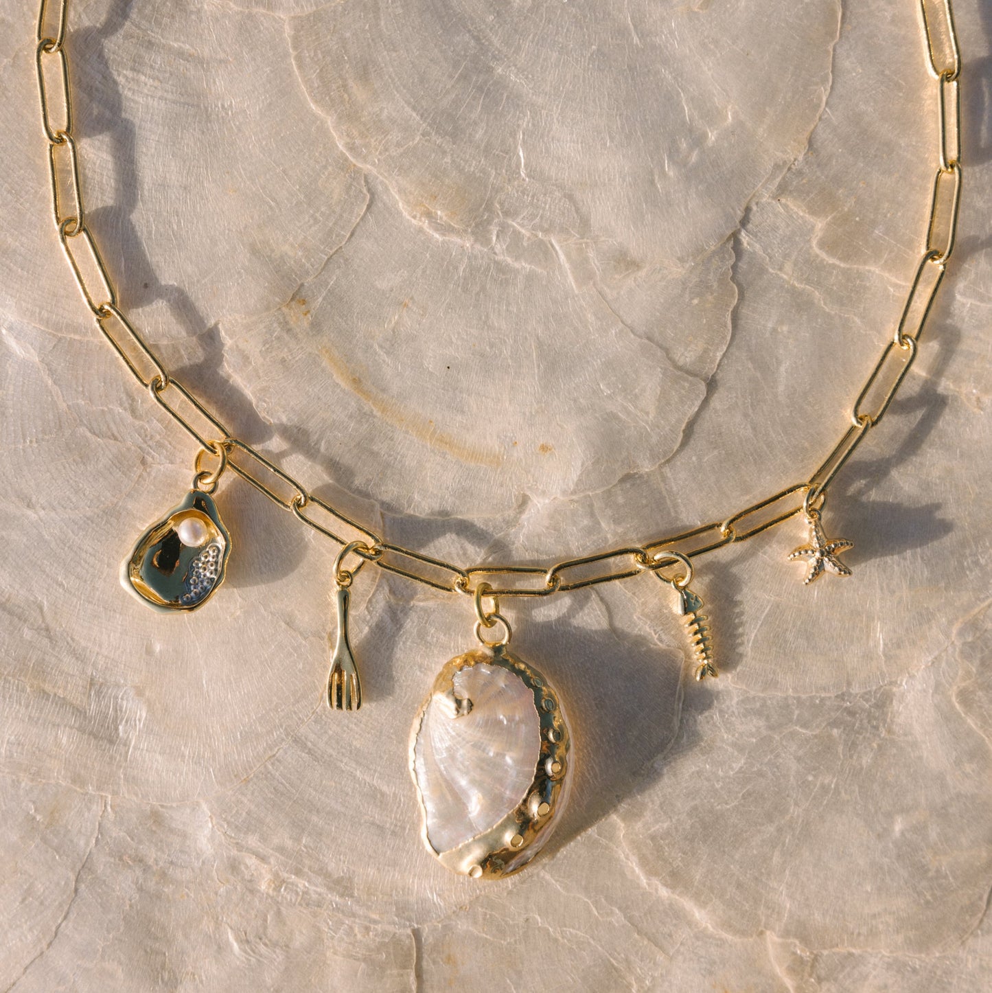 Gold necklace with pendant on a stone surface
