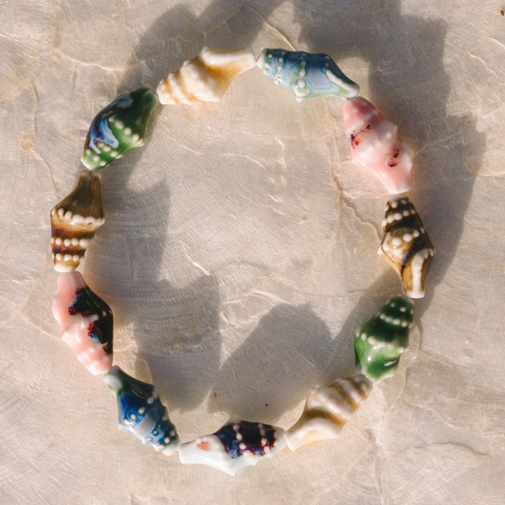 Multicolored seashell bracelet on a textured beige surface
