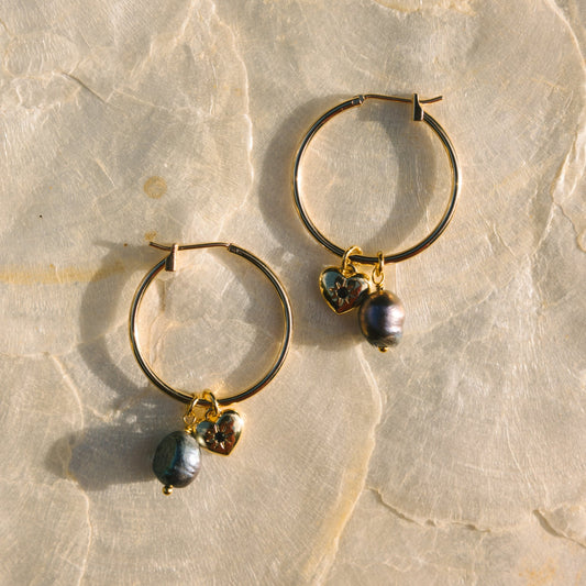Gold hoop earrings with small beads on a marble surface