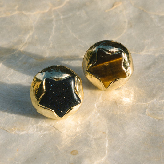 Gold and black stud earrings on a marble surface