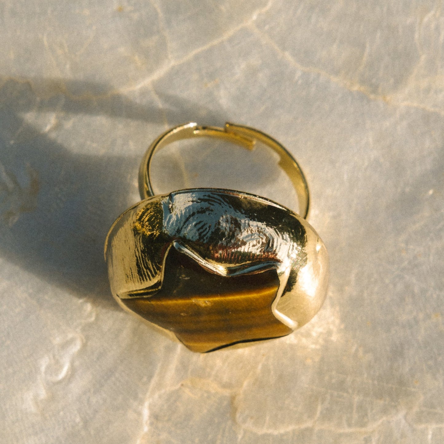 Gold ring on a textured beige surface