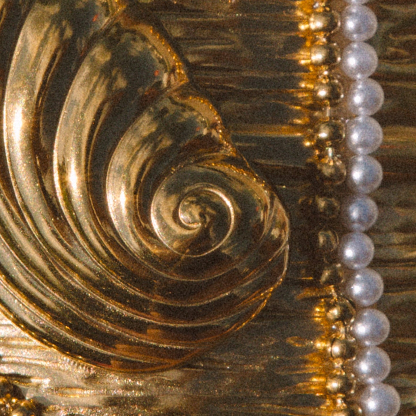 Close-up detail of a gold-toned decorative object with a spiral carved motif.