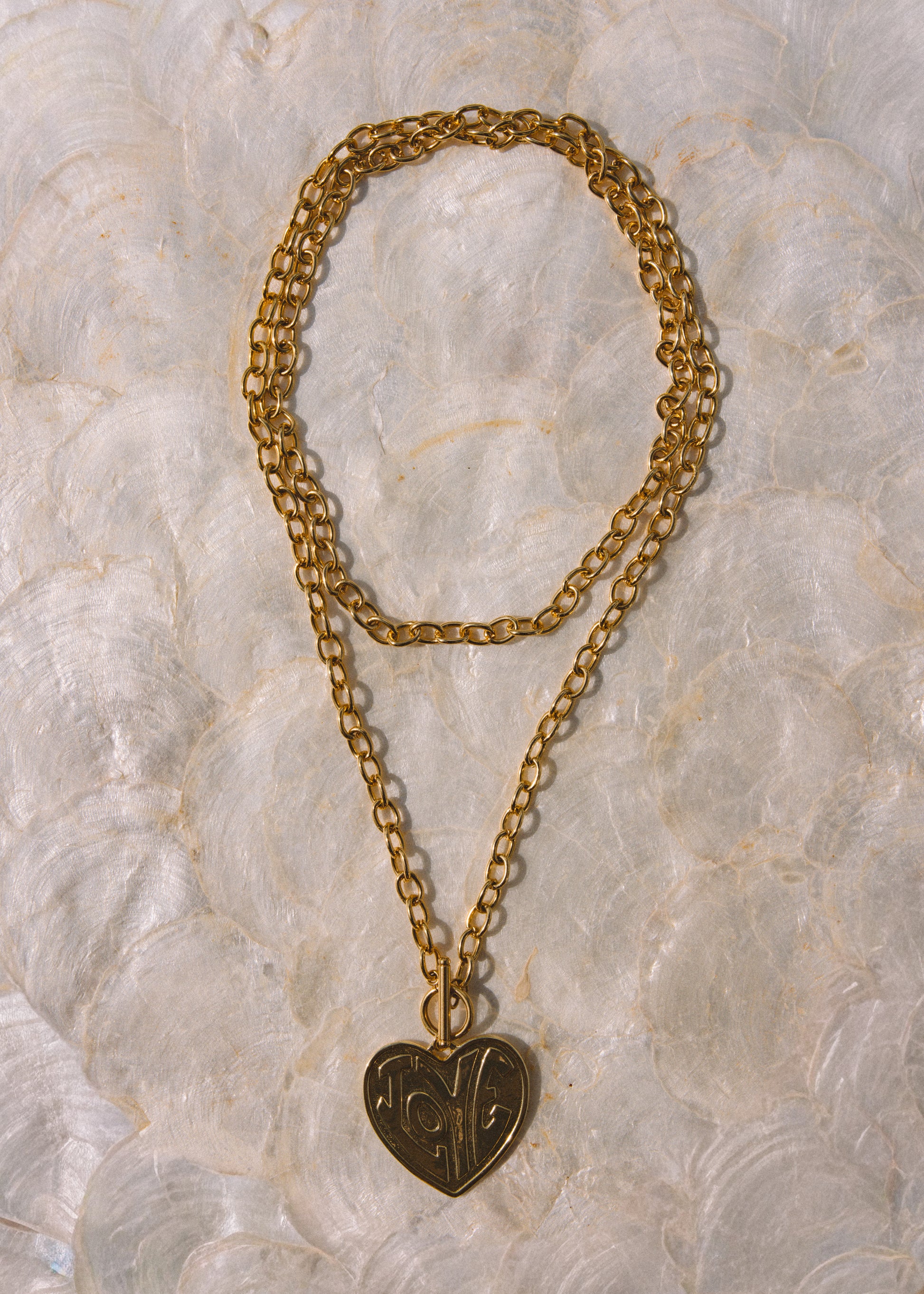 A gold-toned double-strand chain necklace with a heart-shaped pendant featuring engraved initials.