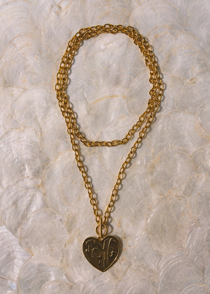 A gold-toned double-strand chain necklace with a heart-shaped pendant featuring engraved initials.