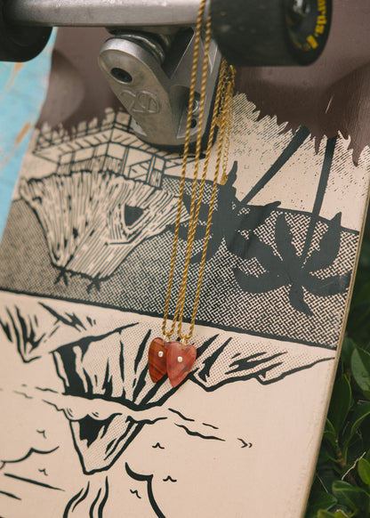 Skateboard with a necklace draped over it, featuring a mountain design.