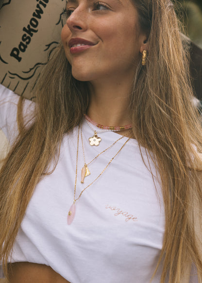 Woman wearing gold necklaces with a white top outdoors