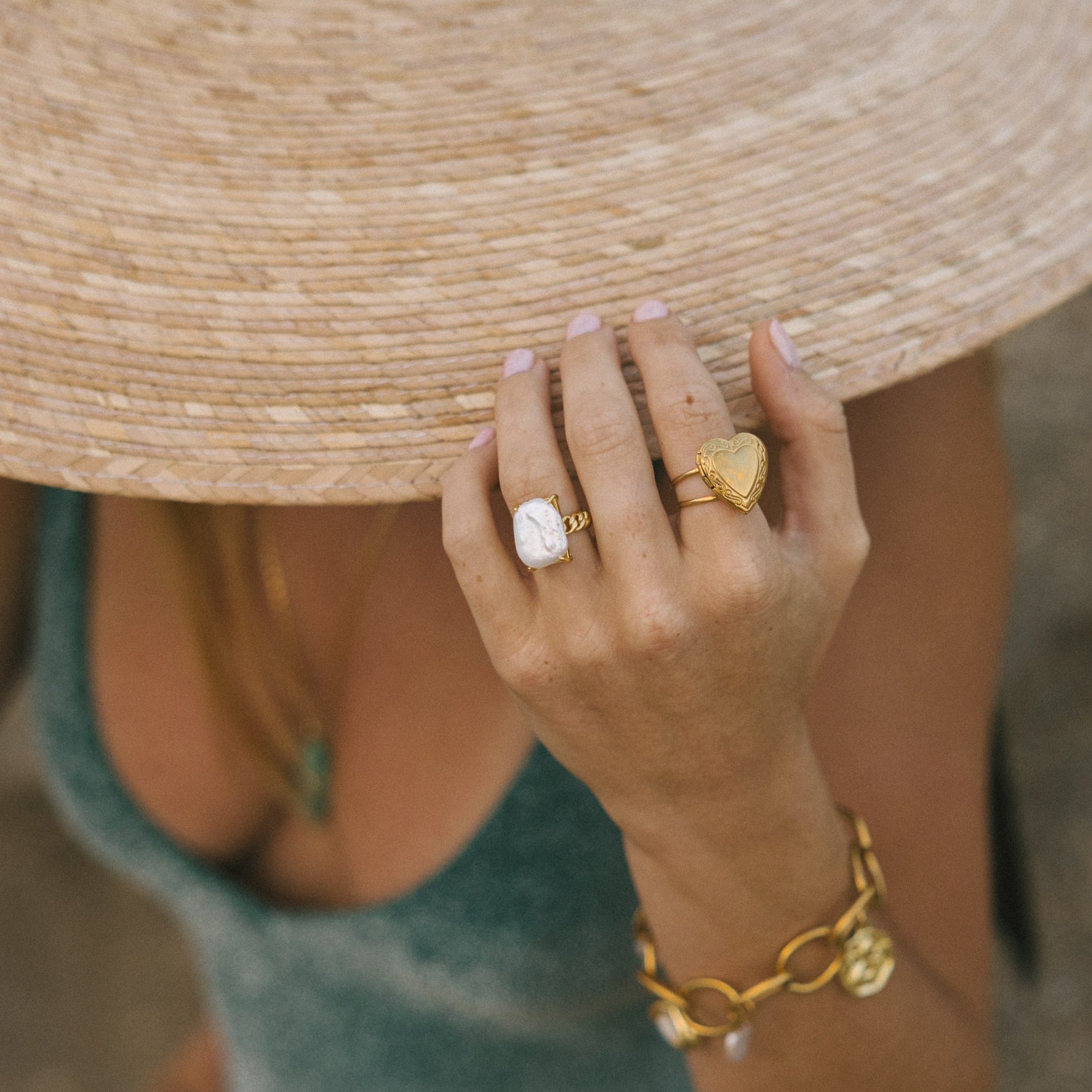 Person wearing a straw hat and gold jewelry on a blurred background