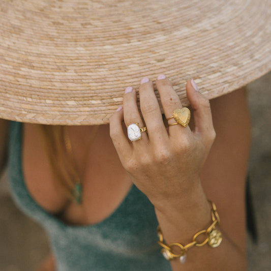 Person wearing a straw hat and gold jewelry on a blurred background
