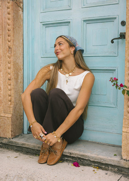 Woman sitting on a step in front of a light blue door with a floral arrangement.