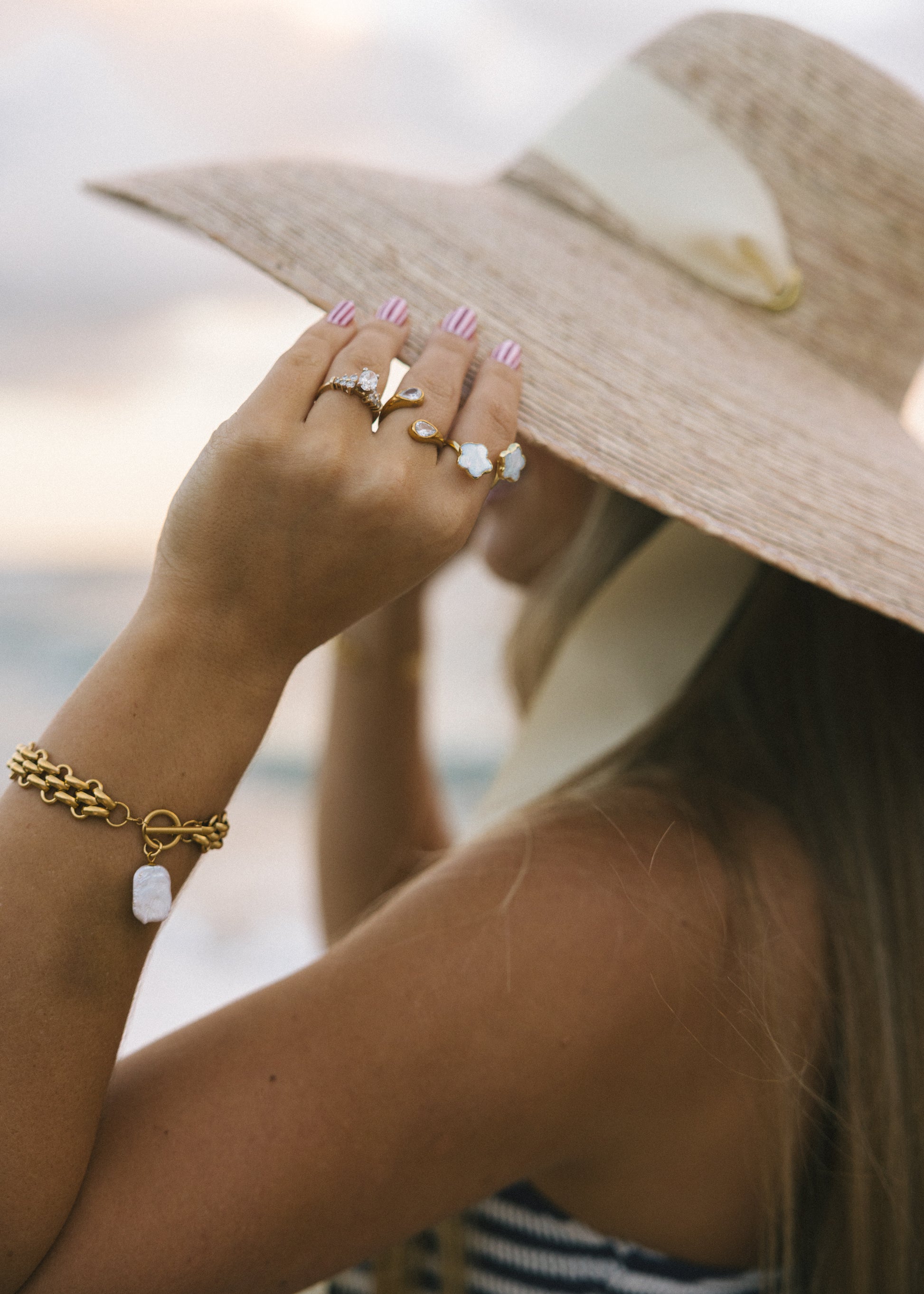 Person wearing a straw hat and gold jewelry with a blurred background